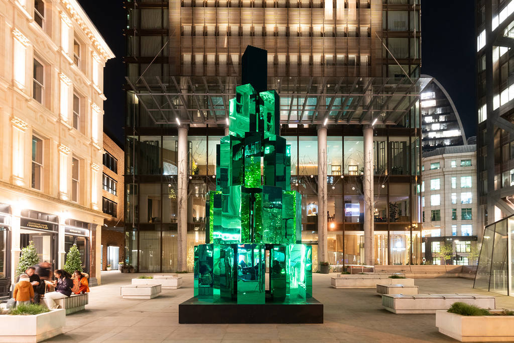 a lit up sculptural installation of green glass, resembling a christmas tree
