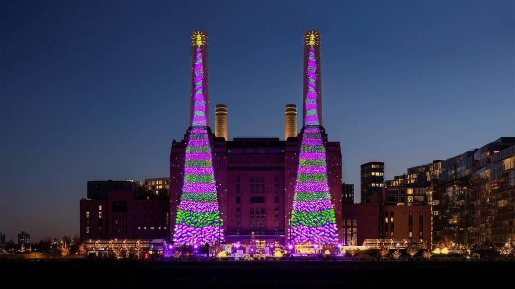 the battersea power station towers lit up by a christmas tree display