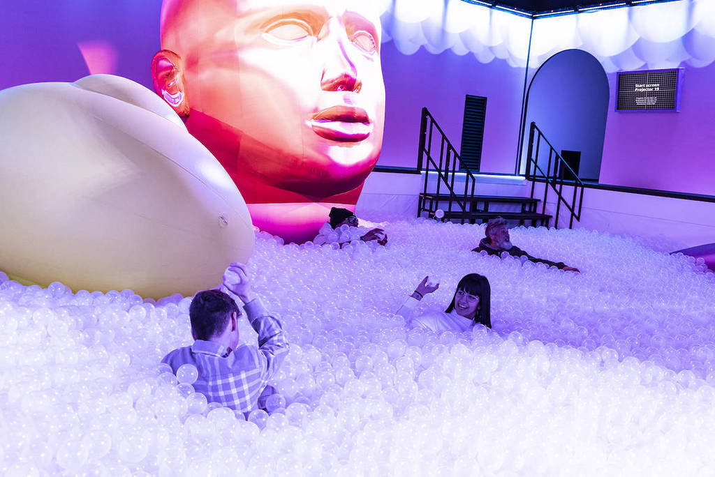 people playing in a bubble pit that fills a whole room