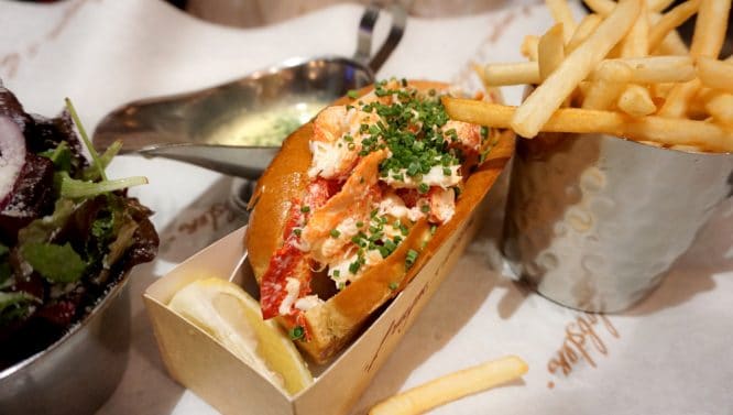 A delicious lobster roll served with a side of chips at Burger & Lobster