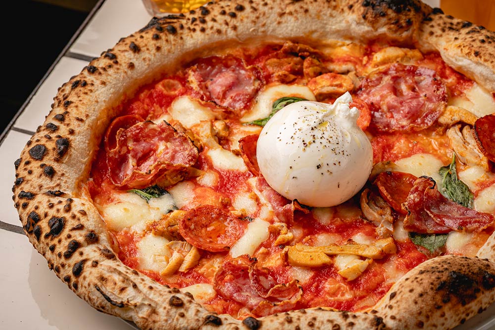 a seven nation salami pizza from Crust Bros, topped with a ball of burrata