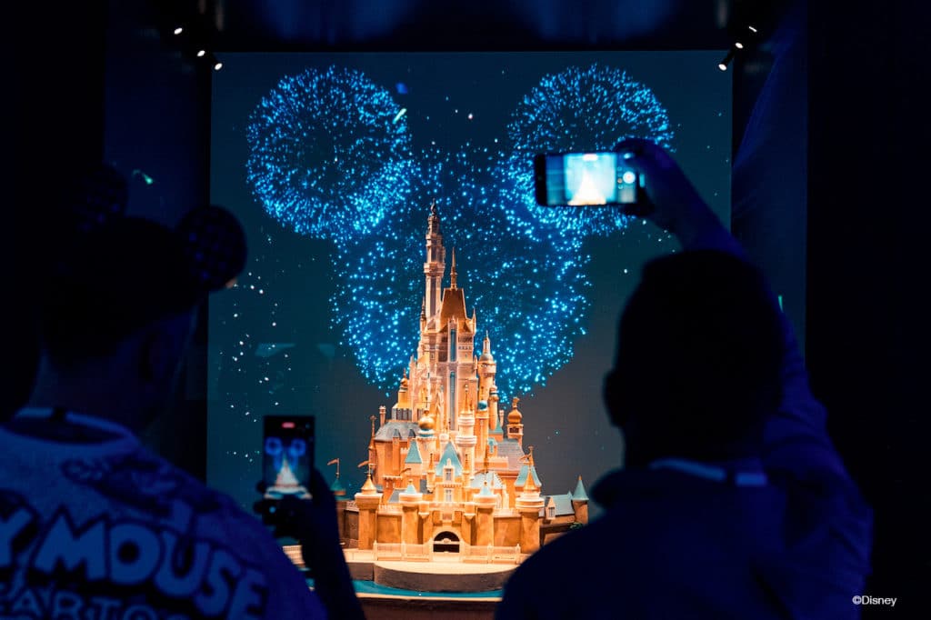 people taking photos of the iconic disney castle at Disney100: The Exhibition