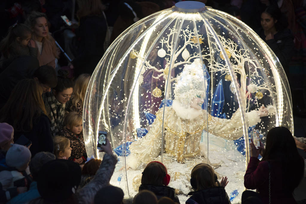 a performer inside a snowglobe costume walking through a crowd