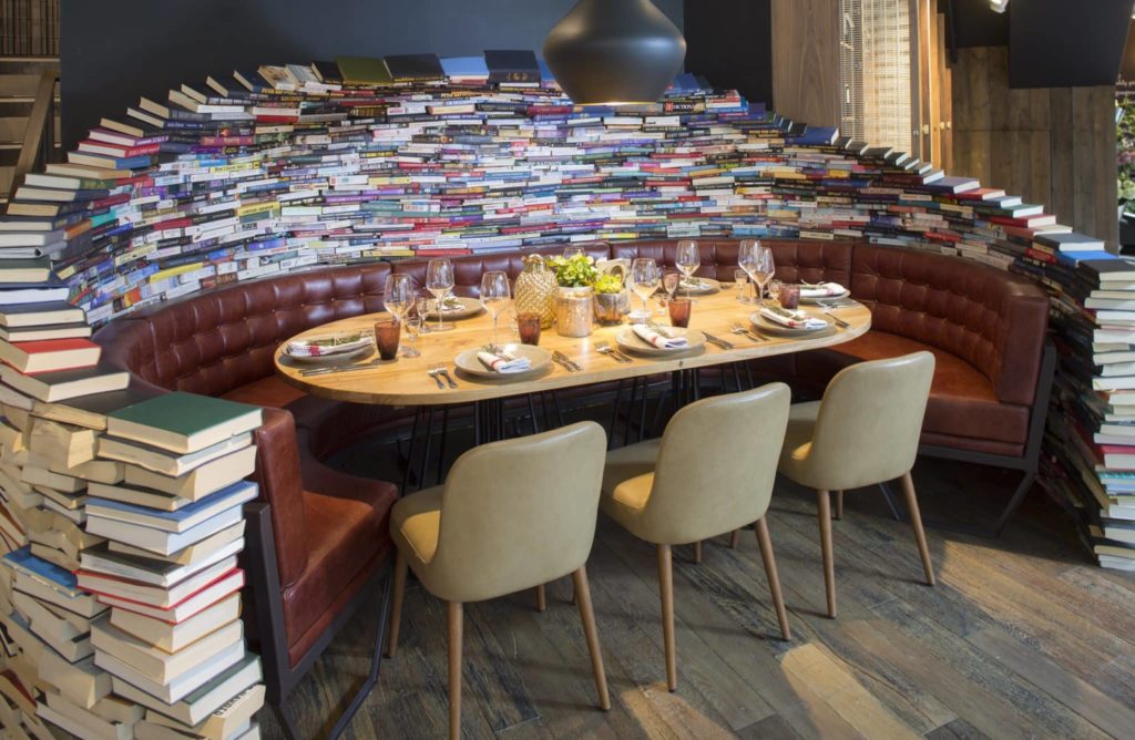 the book table at the fable, where piles of books ring the sofa around the table