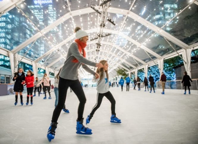 A mother and her child skating around the indoor ice rink at Canary Wharf