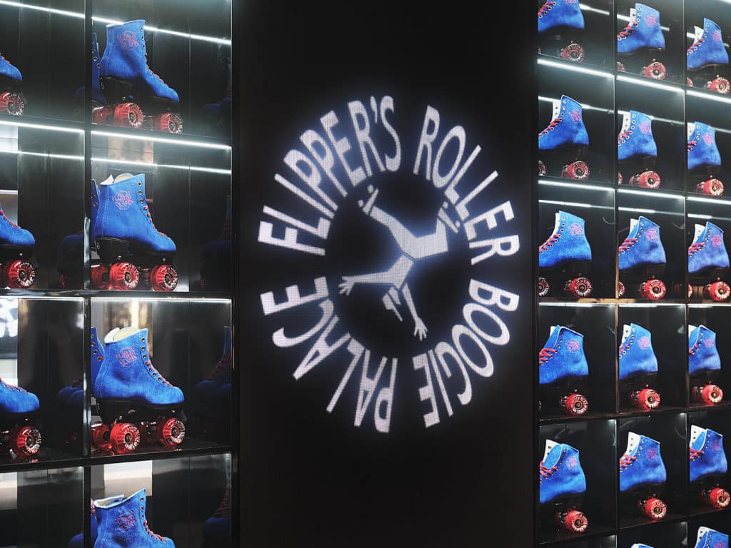 a wall of blue and red skates available for rental, with the flipper's roller boogie palace logo in the middle