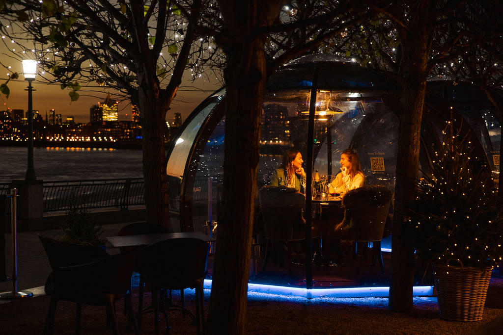 people chatting inside the christmassy dining pods in canary wharf at night