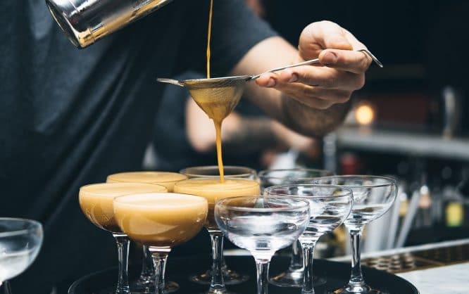 A waiter pouring espresso martinis into a glass at Grind