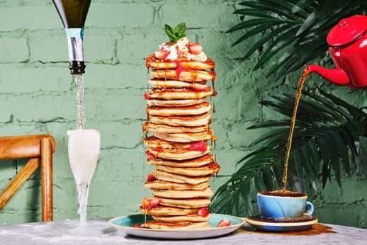 A stack of pancakes with Prosecco and hot drinks served at Bill's