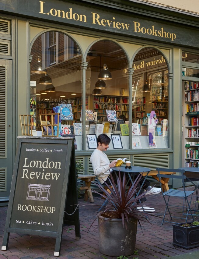 someone sat at a table reading a book outside London Review Bookshop