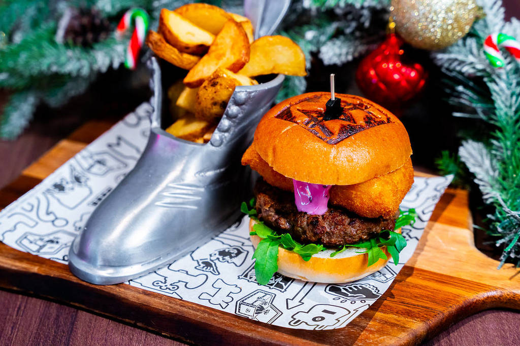 a burger and chips served in a monopoly boot in front of a Christmas tree at Monopoly Lifesized
