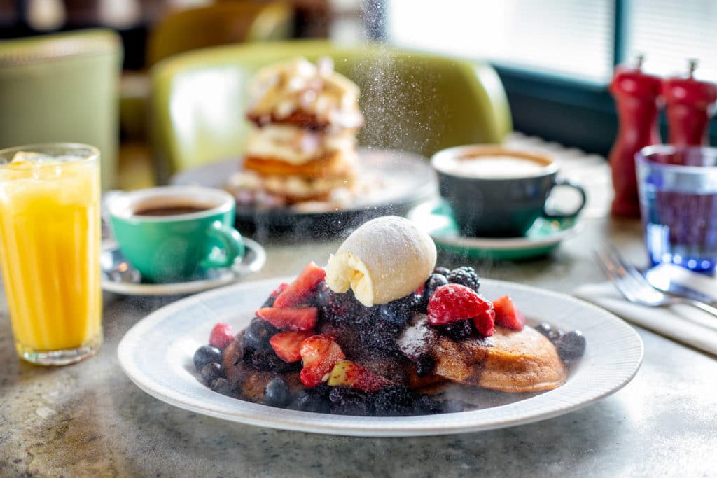 A delicious stack of pancakes covered in ice cream, berries and icing sugar at the Riding House Café