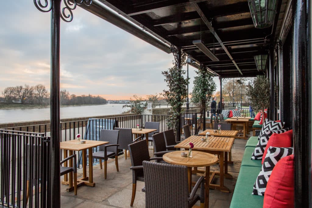 a shot of the covered terrace area of the riverside pub The Old Ship, with the river stretching off into the distance