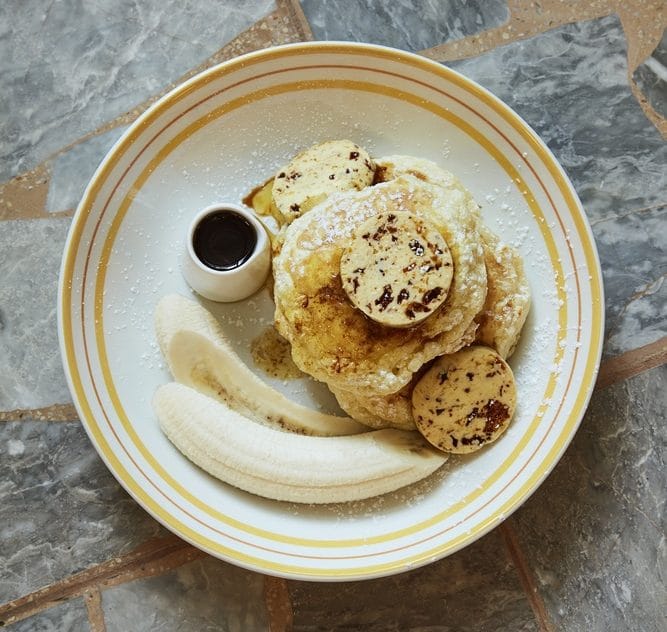 A delicious stack of banana pancakes with a side of maple syrup served at Granger and Co. 