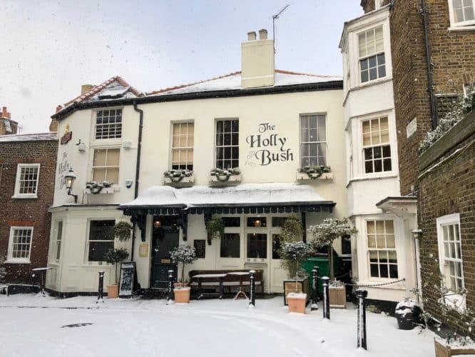 The exterior of The Holly Bush pub in Hampstead covered in snow and decorations