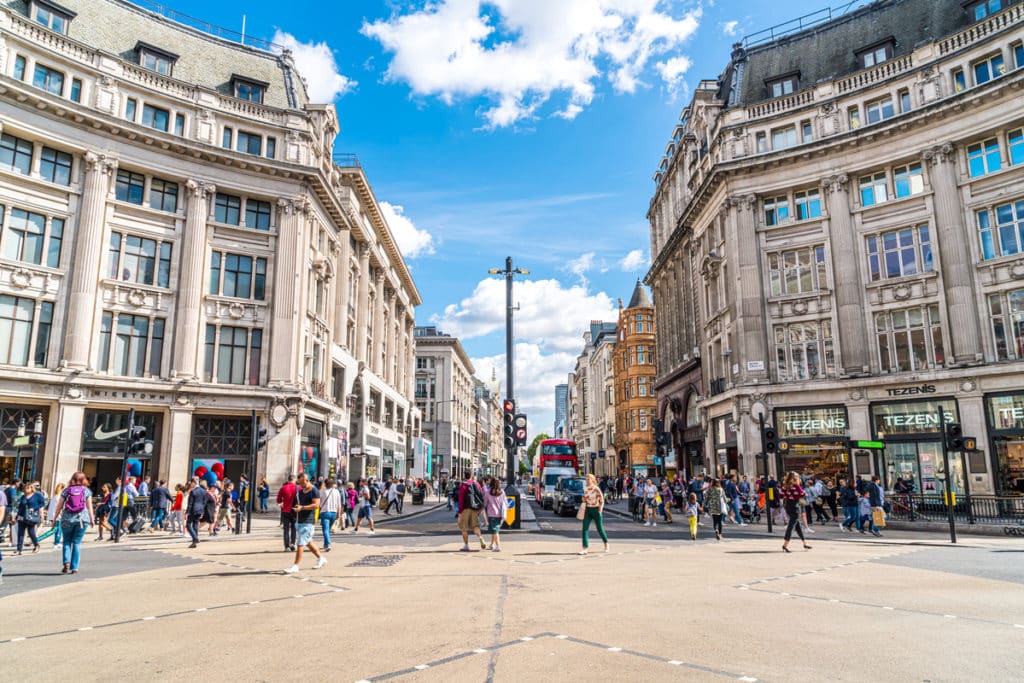 people crossing the road in oxford circus under a blue sky