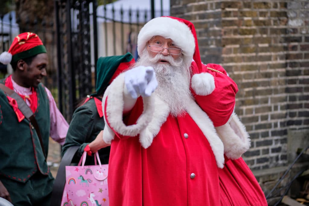 A picture of Santa Claus posing outside of his grotto in London.