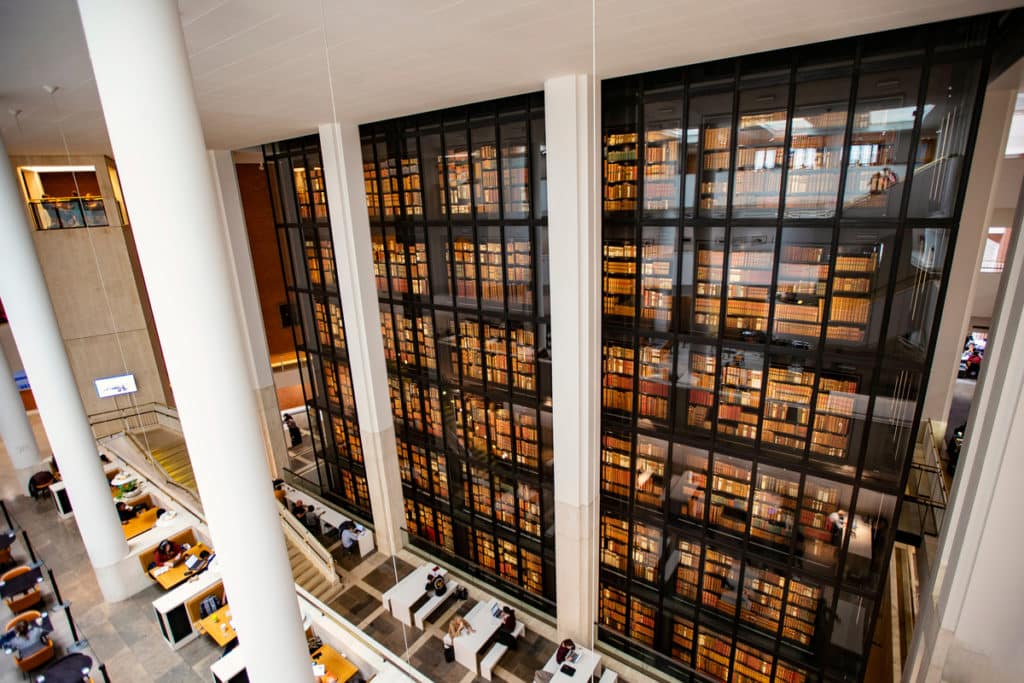 the interior of the british library, showing a vast glass wall protecting thousands of books