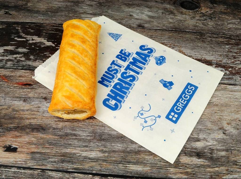 Greggs puff pastry sausage roll with a festive Christmas take away bag design