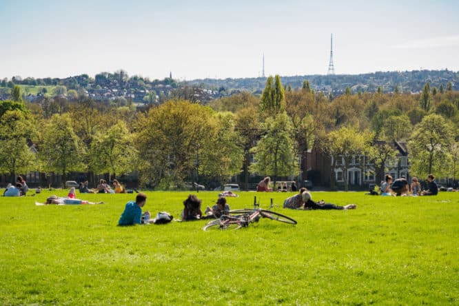 A bright sunny day in Hilly Fields with people relaxing 