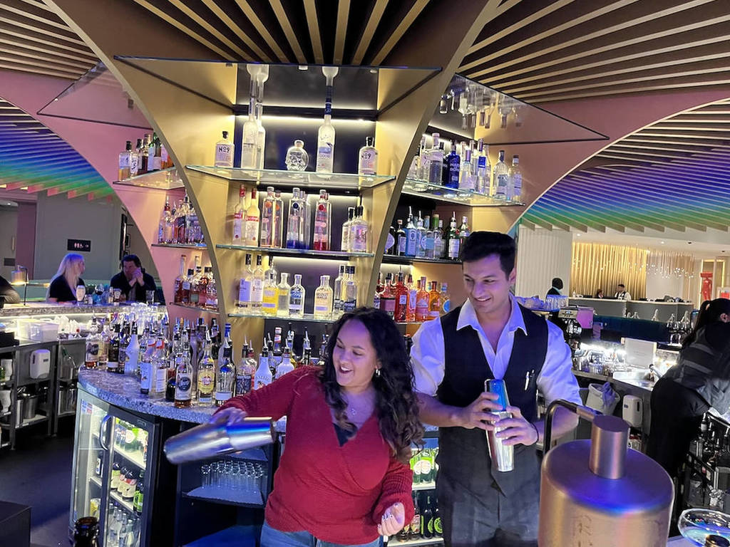 a woman shaking a cocktail shaker under supervision of a bartender at The Cumberland