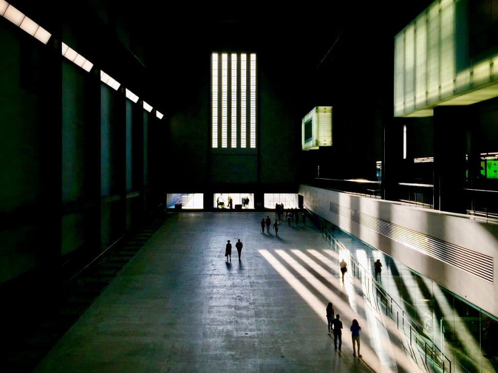 the interior of the tate modern, with striking shadows across the floor from the vertical columns in the wall