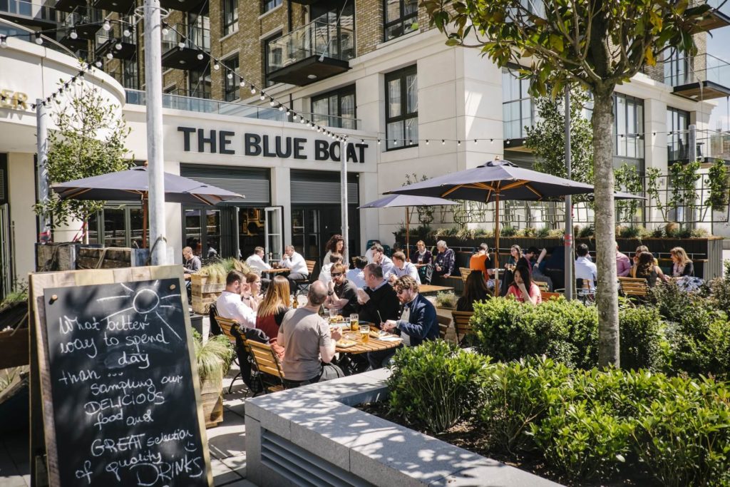 people sitting in the sun outside the blue boat, one of london's riverside pubs