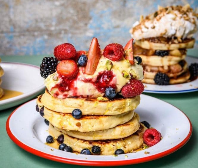 A stack of pancakes covered in berries and yoghurt at The Breakfast Club in London.