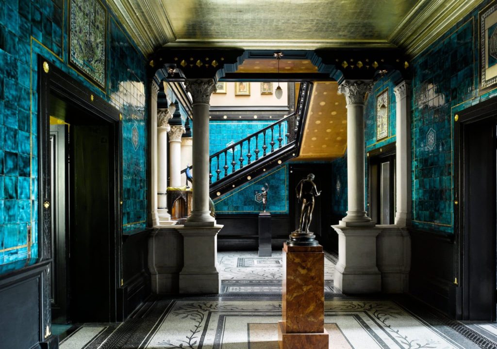 an opulent room with statues on plinths and the walls painted a deep rich blue