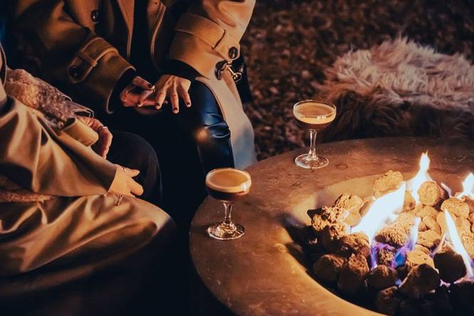 People sat around a fire with cocktails