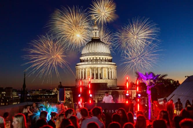 A DJ performing in front of St. Paul's Cathedral surrounded by fireworks in London for New Year's Eve.