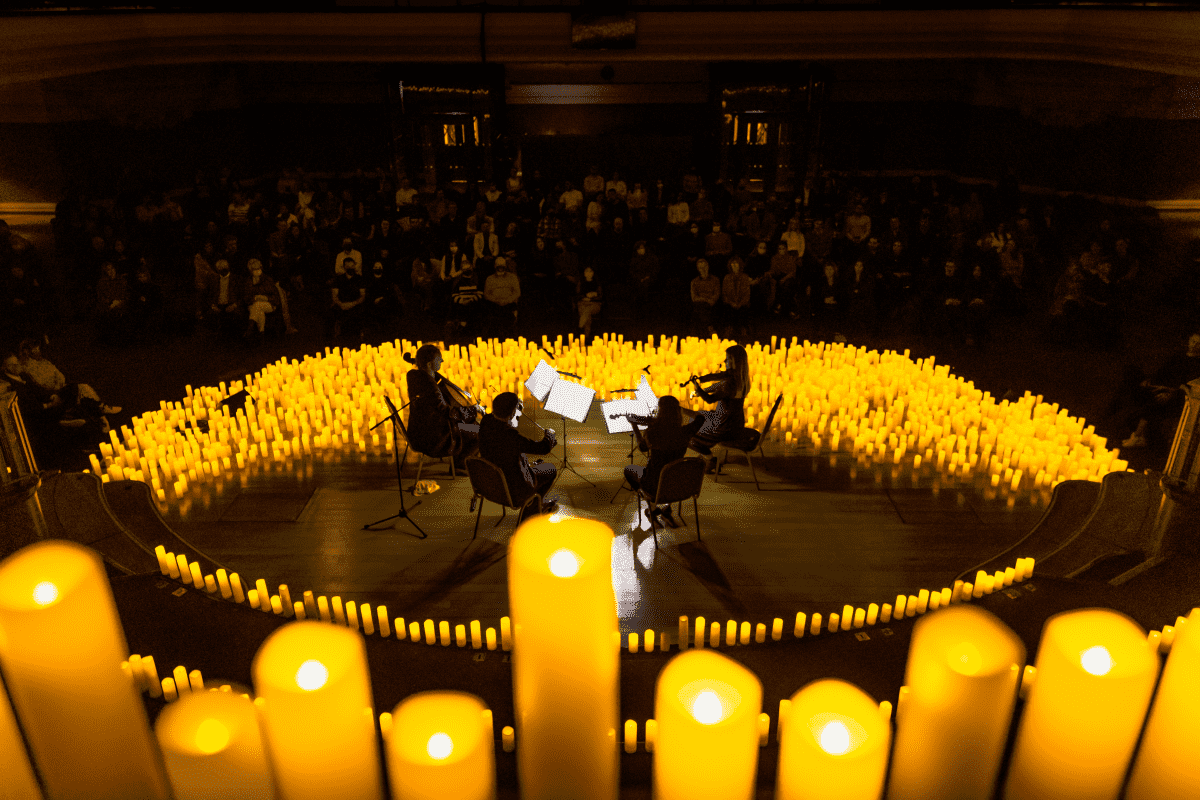 A string quartet visible behind a close-up of candles performing a Candlelight concert at Central Hall Westminster.