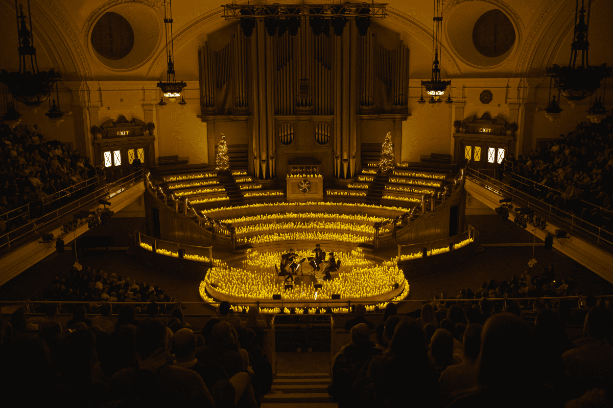 A string quartet performing on stage surrounded by candlelight in Central Hall Westminster. 