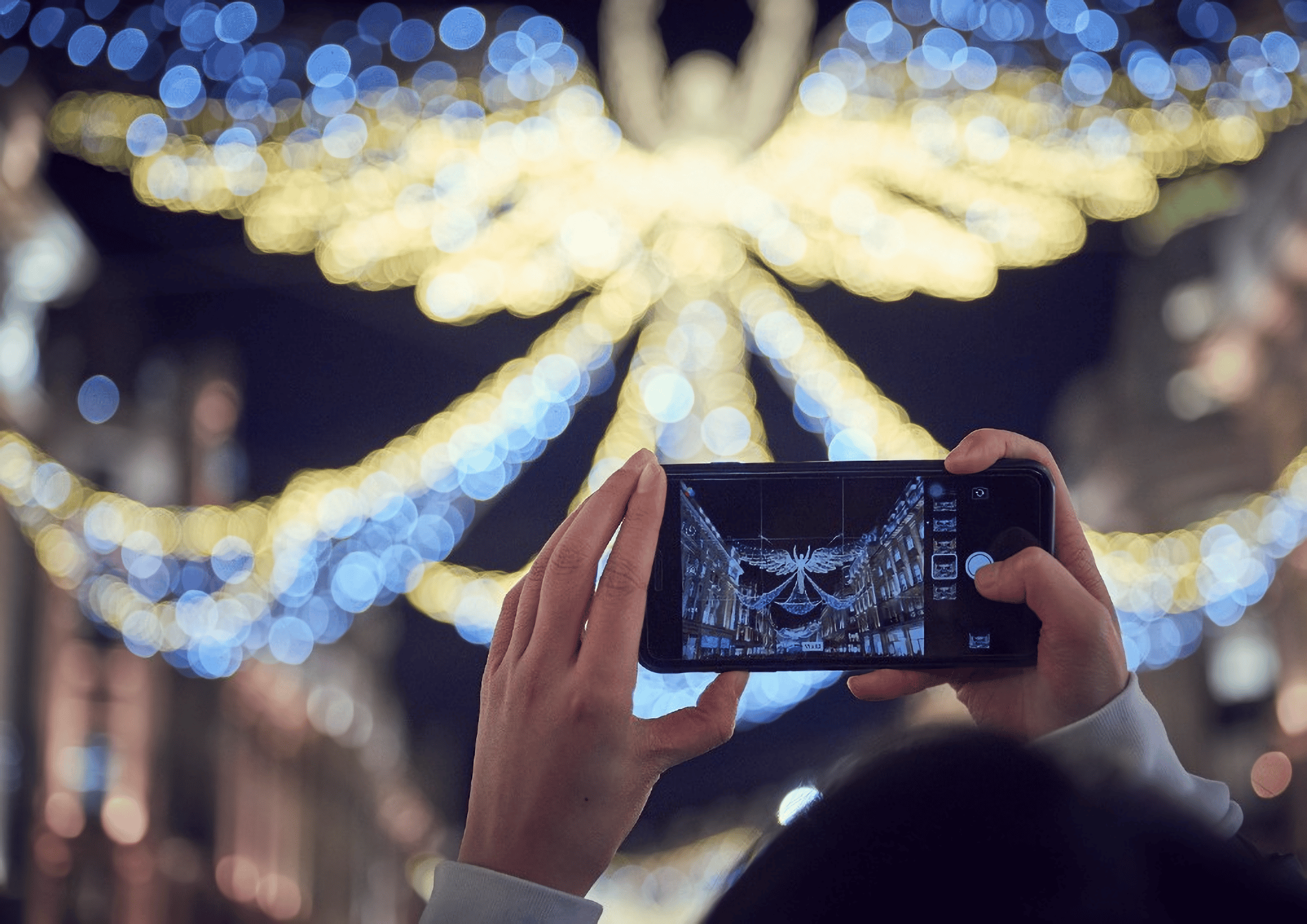 Someone photographing the regent street christmas lights with their iphone